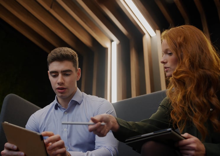 Two warehouse colleagues reviewing improvement actions and safety performance on visual management board in factory