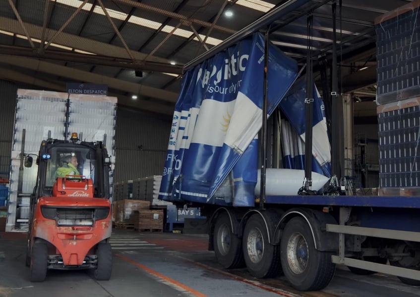 Forklift truck loading goods into HGV at warehouse loading dock