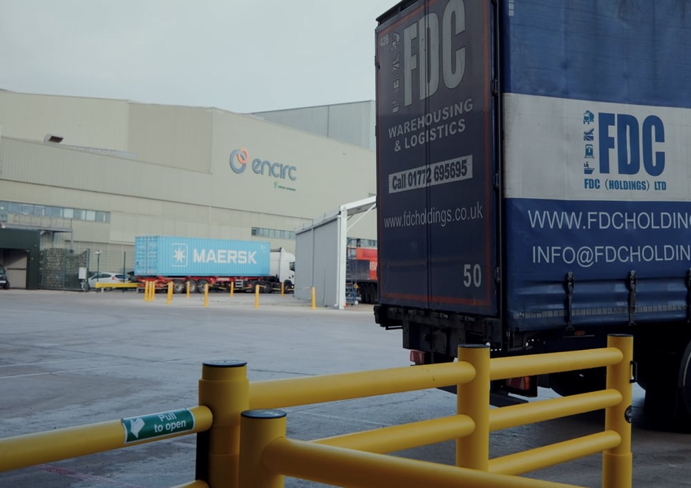 Delivery trailer in warehouse forecourt with yellow polymer barriers segregating vehicle and pedestrian zones