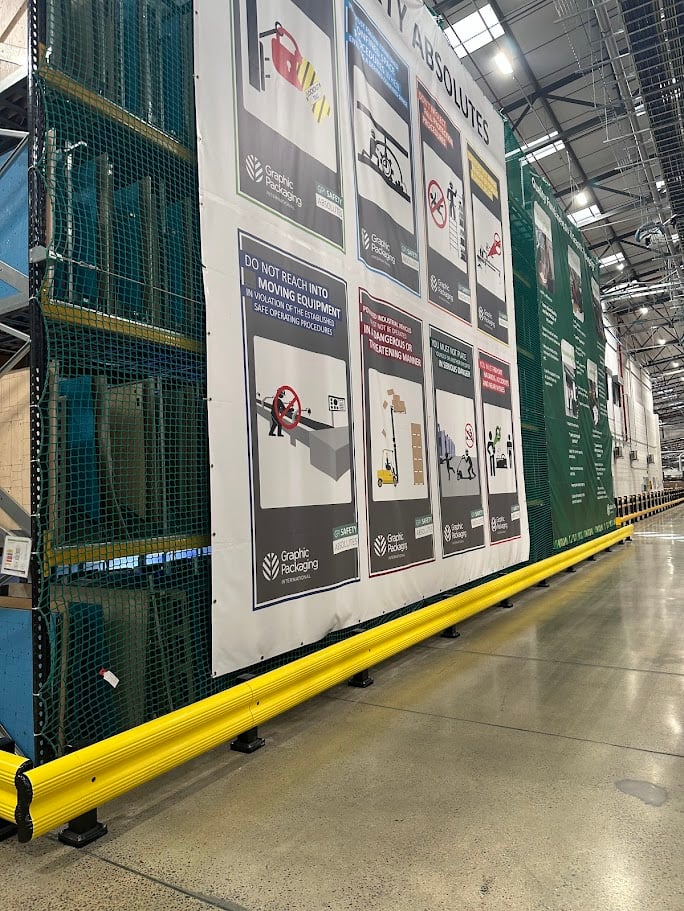 Large warehouse safety sign mounted on wall displaying hazard warnings and safety procedures