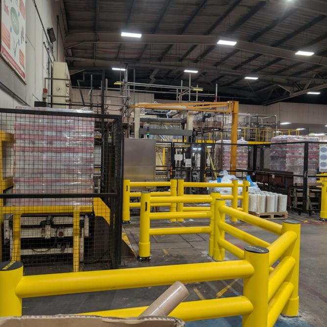 Yellow polymer safety barrier in UK warehouse aisle separating FLT and pedestrian zones