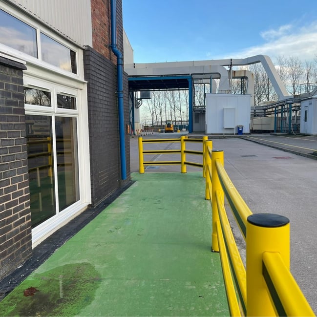 Outdoor warehouse yard with polymer barrier system separating pedestrian walkway from vehicle routes