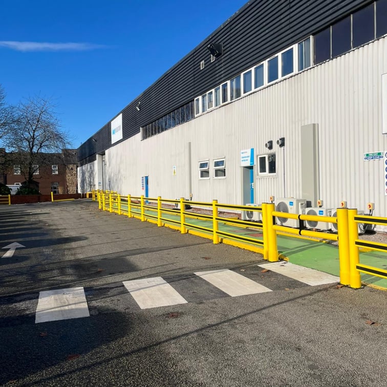 Outdoor pedestrian walkway and crossing with high-visibility markings in warehouse yard showing pedestrian and vehicle segregation