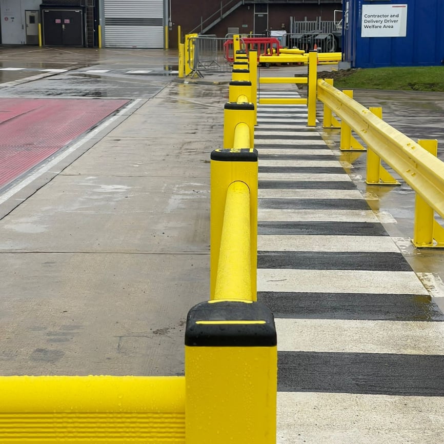 Polymer safety barriers segregating pedestrian walkway from vehicle traffic in outdoor warehouse yard