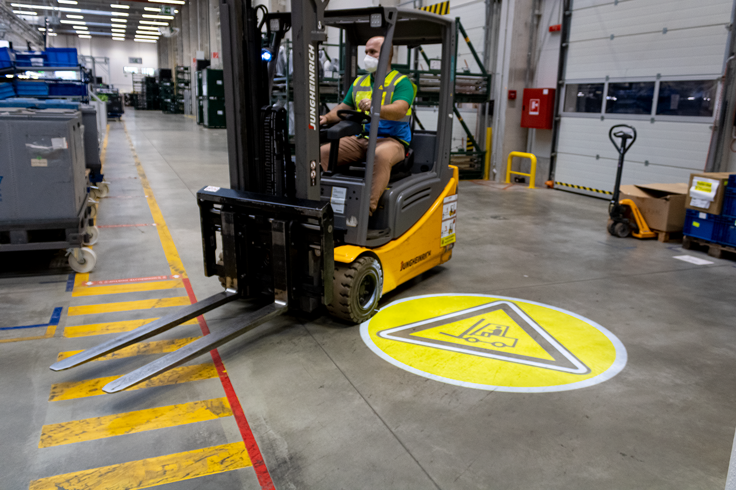 FLT operator driving forklift truck over painted pedestrian walkway highlighting warehouse safety risks