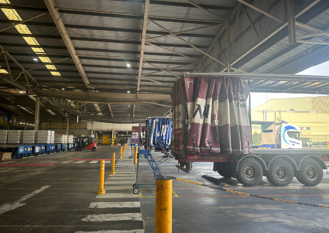 Multiple curtainsider vehicles loading at warehouse dock UK distribution site