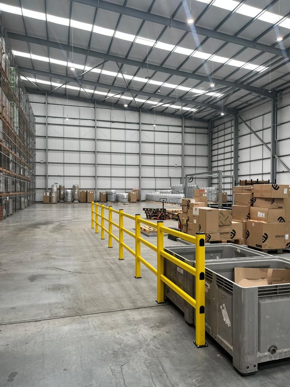 Modular polymer barriers installed alongside warehouse racking in distribution facility