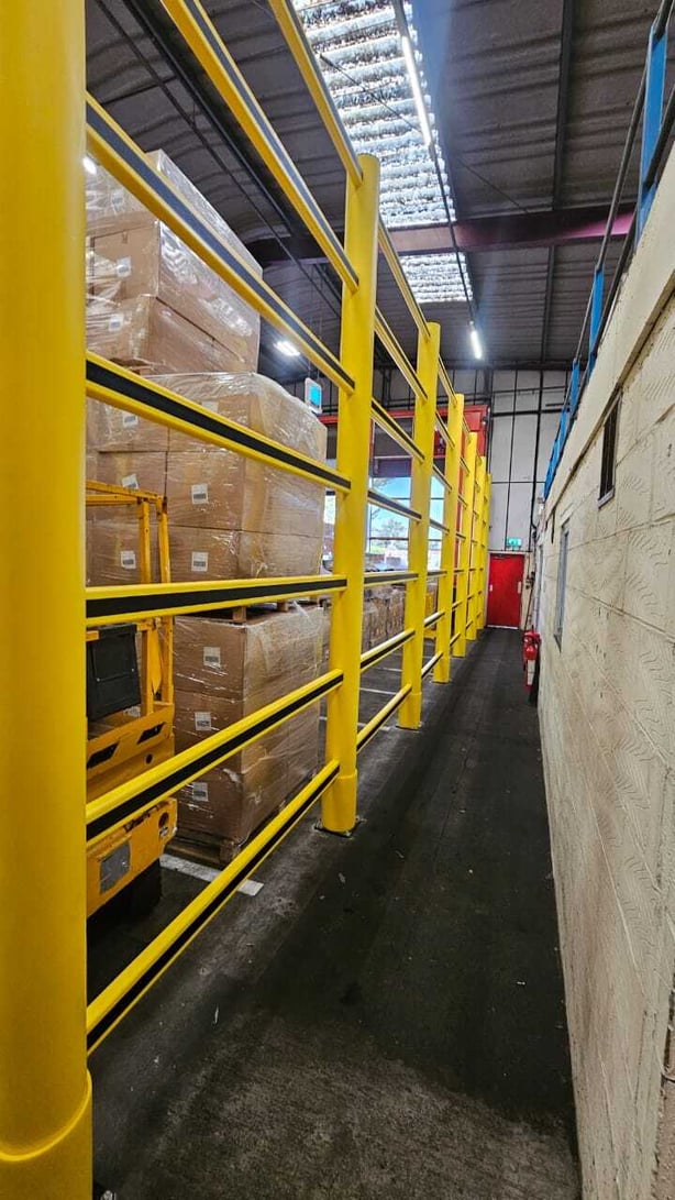 Topple barrier beside block-stacked product in a food processing store