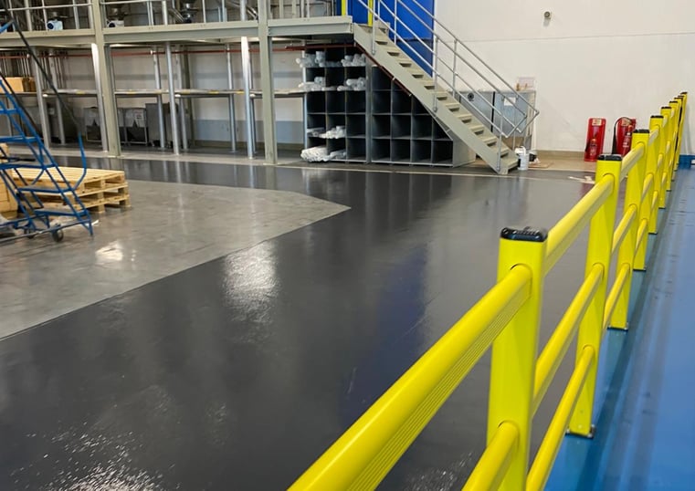 Yellow polymer safety barriers forming a pedestrian walkway in a pharmaceutical warehouse facility