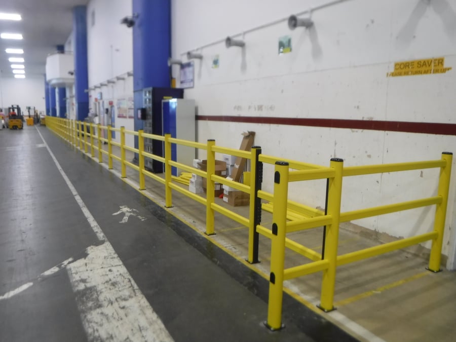 Yellow safety barrier in a UK warehouse protecting pedestrian walkway