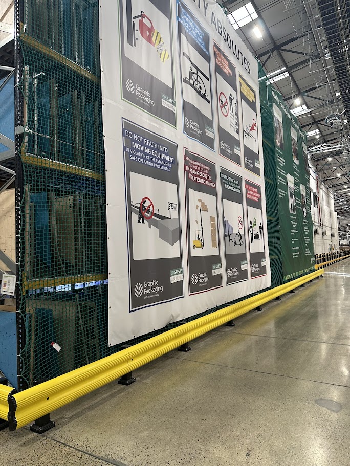 Large warehouse safety sign mounted on wall displaying hazard warnings and safety procedures