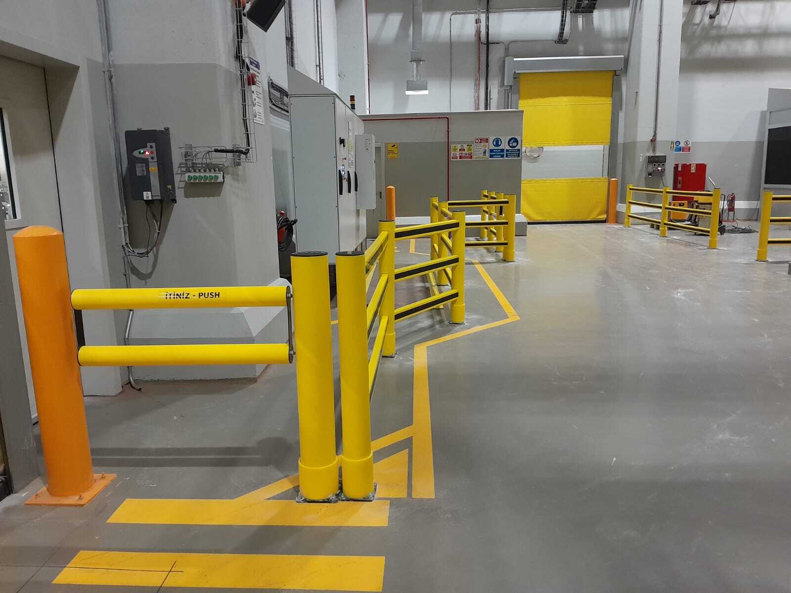 Polymer pedestrian barriers and safety gate at airlock roller door in warehouse facility
